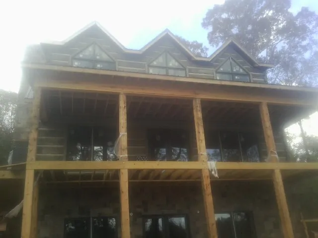 Dormers and porch framing on a large log home under construction — Roof Coating work by our crew in Malibu